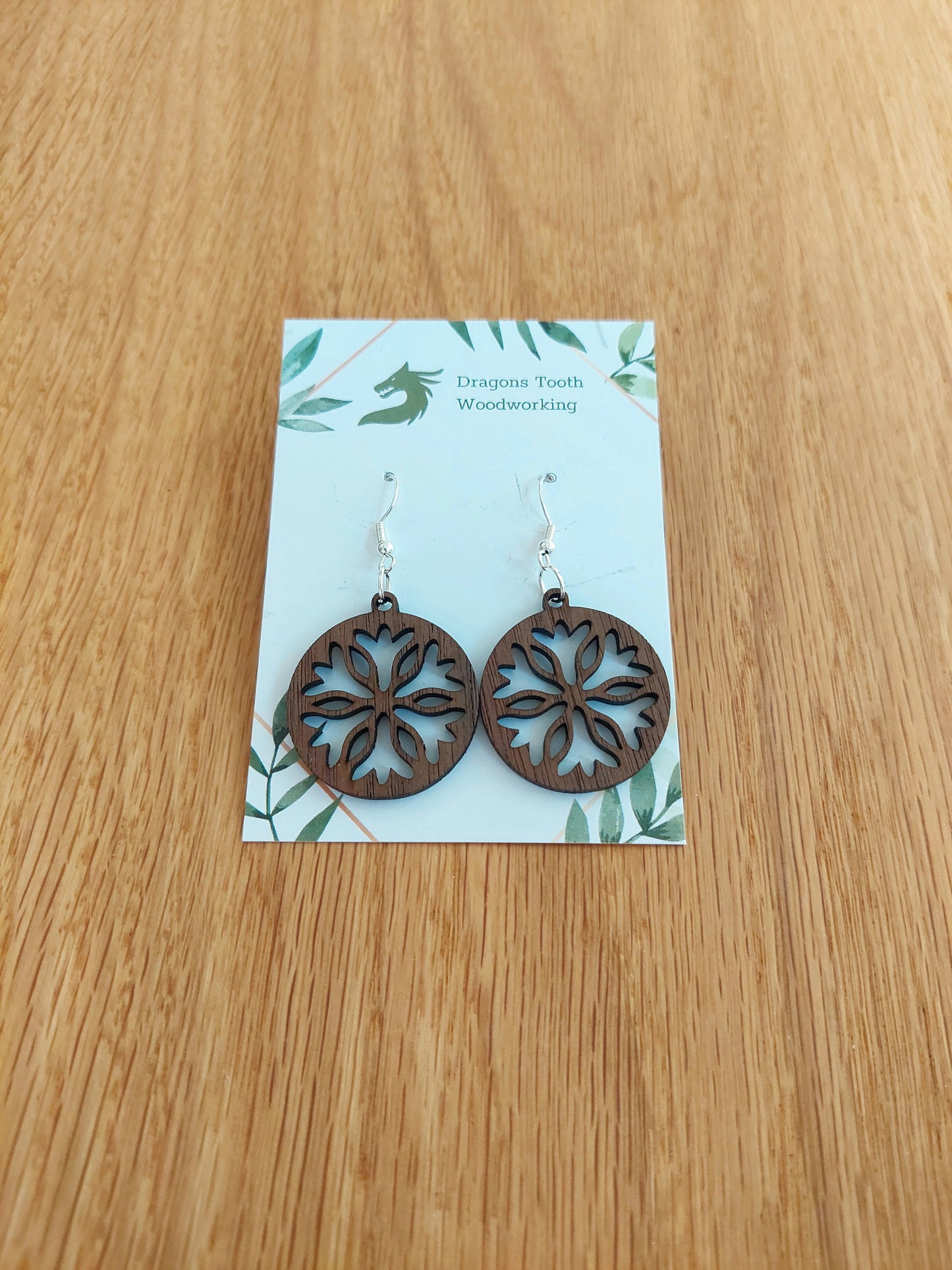 A front view of the classic snowflake silhouette earrings crafted from rich, deep chocolate-brown solid Walnut wood, displayed on an earring card.