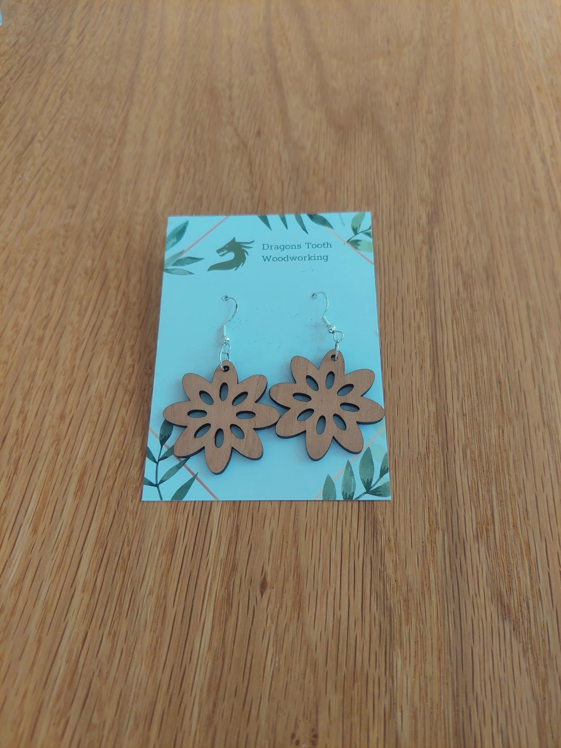Handcrafted cherry wood daisy flower earrings showcasing a warm caramel-toned natural wood grain with sterling silver hooks.
