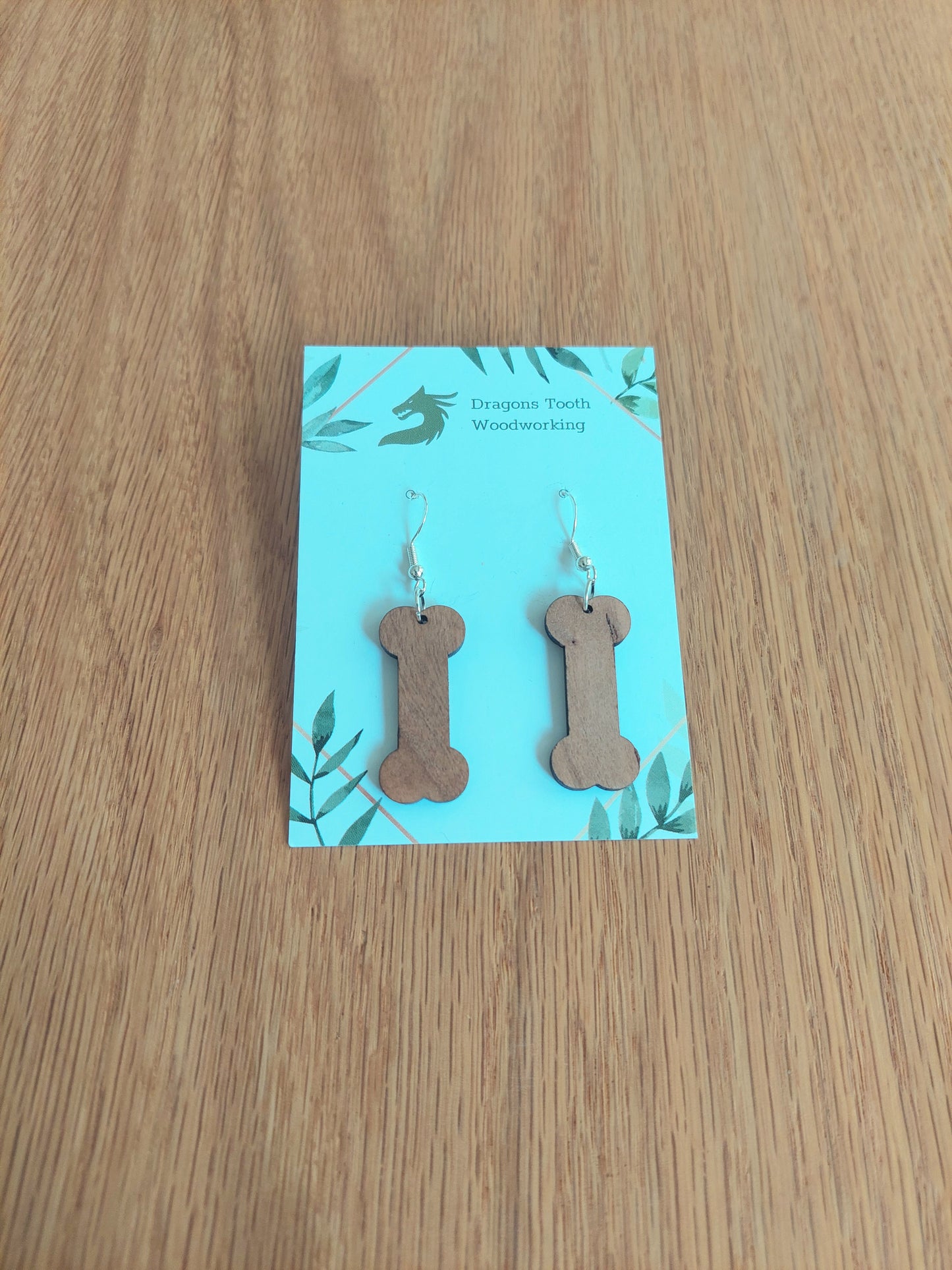 Handcrafted cherry wood dog bone earrings showing off a rich, caramel-colored natural wood grain with hypoallergenic hooks.