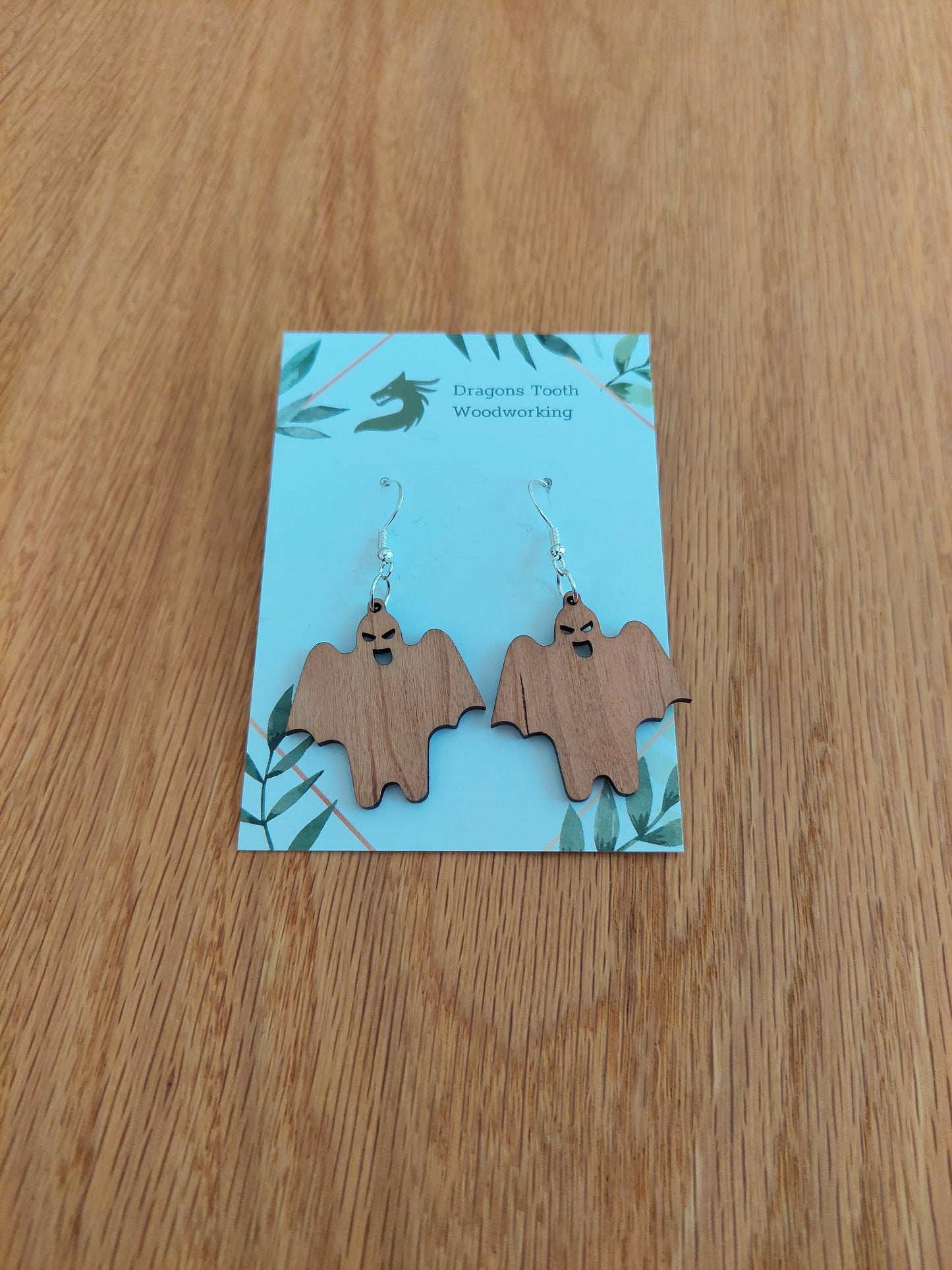 Handcrafted cherry wood ghoul ghost earrings showcasing a warm caramel-colored natural wood grain with hypoallergenic hooks.
