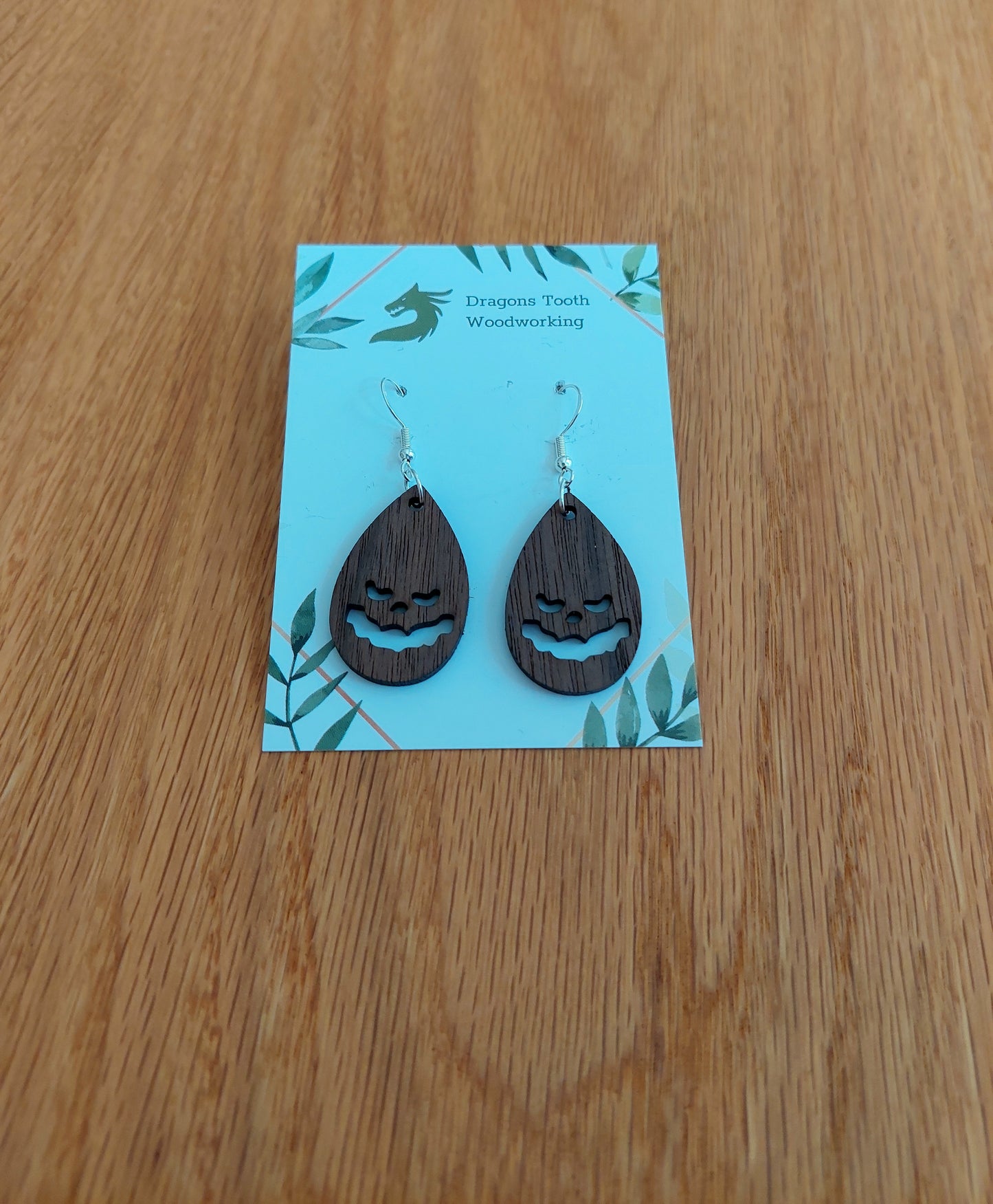 Deep chocolate brown walnut wood jack-o-lantern teardrop dangle earrings, unique handcrafted spooky autumn jewelry.