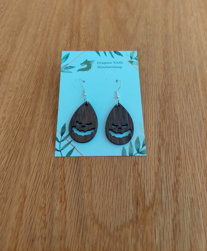 Deep chocolate brown walnut wood jack-o-lantern teardrop dangle earrings, unique handcrafted spooky autumn jewelry.