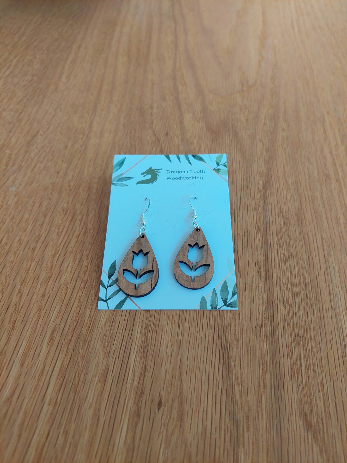 Handcrafted cherry wood tulip flower earrings showcasing a warm caramel-toned natural wood grain with hypoallergenic hooks.